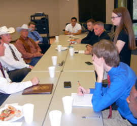 A group of students and adults sitting across from three Texas Rangers.