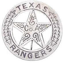 A silver circle star badge with the word "Texas" at the top of the circle and "Ranger" at the bottom. In the center of the star is the words "Co. A". There are leaves up the side of the circle and swirls in the middle of the star.