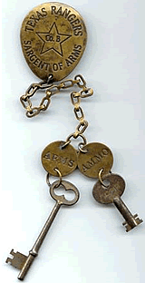 A brass key ring with two keys on it. The key ring says "Texas Rangers Sargent of Arms Co. B" and one key is labeled "Arms" and the other "Ammo".