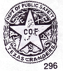 A drawing of a circular badge with a star in the center and leaves along the side. Alternating with the points of the star are the letters that spell "Texas" and in the center of the star are the words "CO. F". Accross the top of the star are the words "Dept. of Public Safety". Across the bottom of the circle are the words "Texas Rangers".