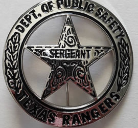 A silver circle star badge with the words "Dept. of Public Safety" across the top of the circle and the words "Texas Rangers" across the bottom. There are two branches going up the sides of the circle. In the middle of the star is the word "Sergeant" and there are decorative swirls in the star.