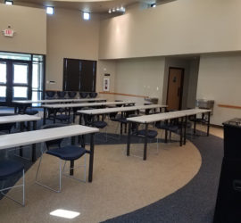 A room with tables and chairs set up like a classroom facing a podium.