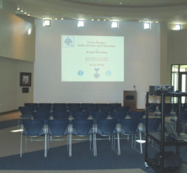 A PowerPoint presentation being projected in front of chairs set up theater style.