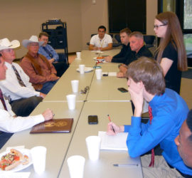A group of students and adults sitting across from three Texas Rangers.