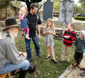 A group of children and one adult speaking to an older man dressed as a Ranger from the 1800s.