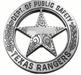 A silver circle star badge with the words "Dept. of Public Safety" across the top of the circle and the words "Texas Rangers" across the bottom. There are two branches going up the sides of the circle. In the middle of the star is a blank space and there are decorative swirls in the star.