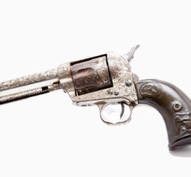 A pistol with engraving along main part of the gun and a carving of a horse and an eagle on the grips.
