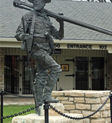 Bronze outdoor statue of a man standing with surveying equipment