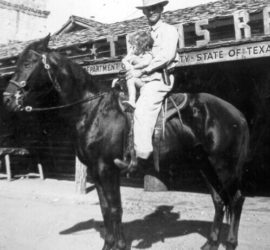 A man in a suite and cowboy hat sitting on top of a horse with a young girl also in the saddle. They are in front of a Texas Ranger DPS building.