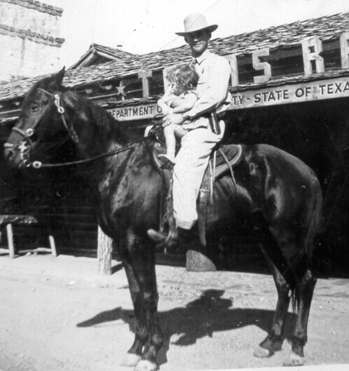 A man in a suite and cowboy hat sitting on top of a horse with a young girl also in the saddle. They are in front of a Texas Ranger DPS building.