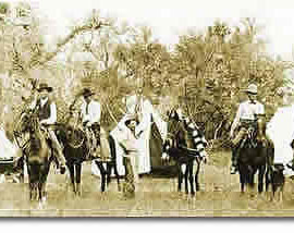 Four Rangers on horseback, one on foot next to his horse, and one dog in front of the tents of a camp.