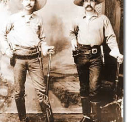 Two men dressed in 1890s Ranger gear posing for a photograph in wide brimmed hats carrying their rifles.