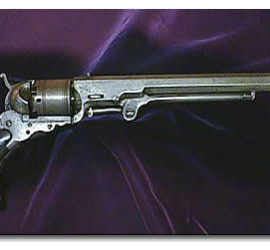 A silver colored metal revolver pistol with polished wooden grips.
