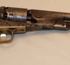 A dark silver metal pistol with some discoloration and bone or ivory grips with an eagle engraved on it.