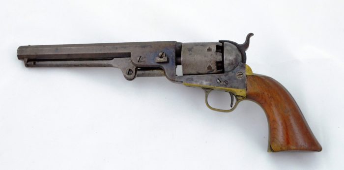 A pistol with wooden grips and a brass trigger and trigger guard.
