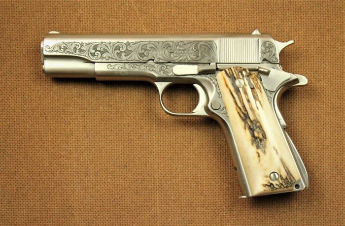 A silver automatic pistol with an antler grip and engraving along the silver parts of the gun.