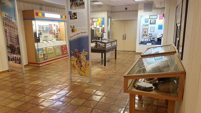 A picture of a colorful exhibit gallery with six visible exhibit cases and two large panels.