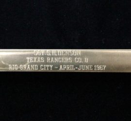 A silver spike with the following words on it "Sgt. S. H. Denson Texas Rangers Co. D Rio Grand City - April - June 1967".