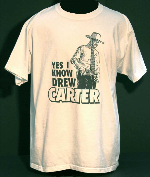 A white t-shirt with the words "Yes I Know Drew Carter" printed on it and a drawn image of a man in a cowboy hat, dress shirt and tie, and a western gun belt.