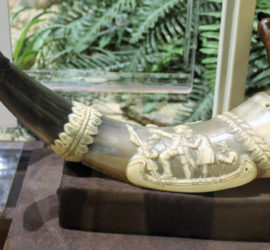 A powder horn with a carving of men standing in a boat.