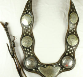 A dark brown leather horse collar with silver decorations.