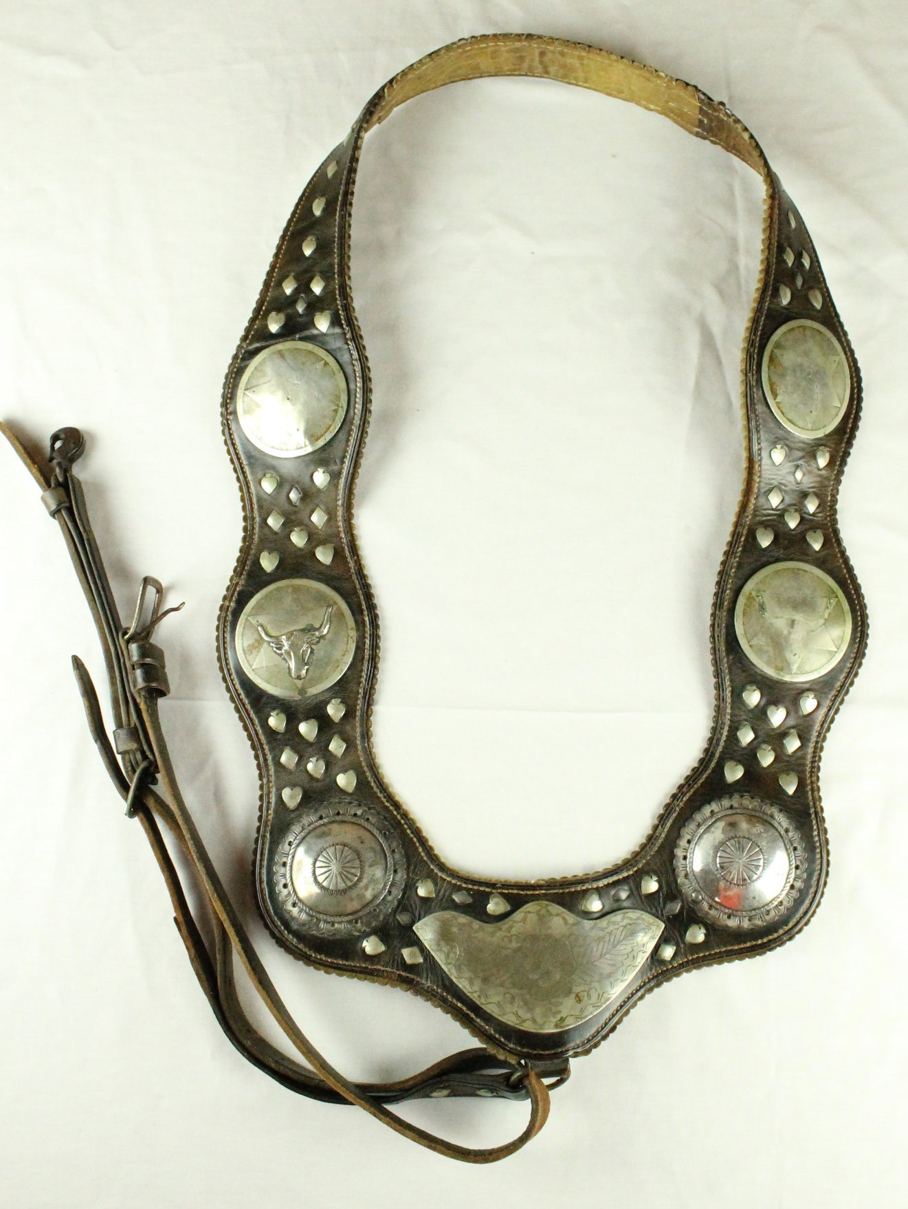 A dark brown leather horse collar with silver decorations.