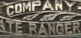 A close up image of a decorative silver surface that reads "Company -B- State Ranger Force".