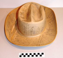 A tan cowboy hat with multiple black signatures covering it.