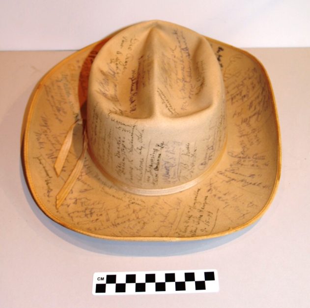 A tan cowboy hat with multiple black signatures covering it.