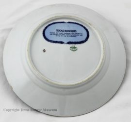 A white plate with a blue oval of writing surrounded by a dark blue rope outline on it.