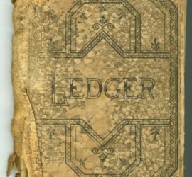 An old tan colored book in tattered condition with a dark blue/black geometric design on it and the word "Ledger"