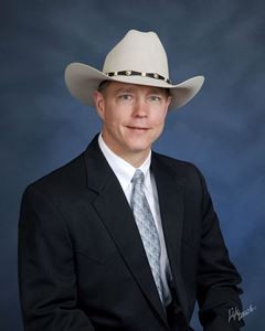 man in white cowboy hat and black suit on blue background