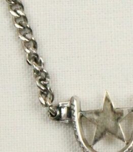 silver star connected to small bar and then a chain