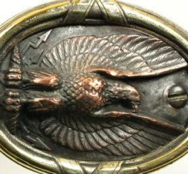 Bronzed metal. Eagle inside circular frame.
