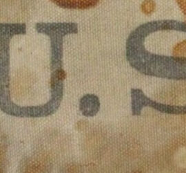 gray letters US on stained brown fabric