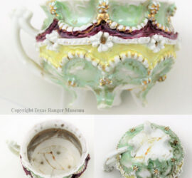 sculptural cup with handle and feet. white flowers between beaded strands on green top and yellow bottom