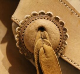 tan leather floral shaped button with leather ribbon through center