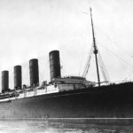 A large early 1900s steam ship with four large steam stacks.